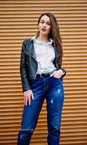 portrait-of-stylish-young-girl-wear-on-leather-jacket-and-ripped-jeans-background-shutter-texture-street-fashion-model-style